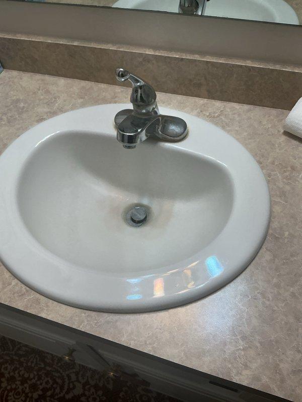 Completed full bathroom sink replacement including installation of new drop-in oval basin with chrome single-handle faucet, new pop-up drain assembly, and new shutoff valves for both hot and cold water supply lines. All plumbing connections were secured, tested for proper operation and leaks, with flexible supply lines properly connected to shutoffs and P-trap drain configuration confirmed functional.