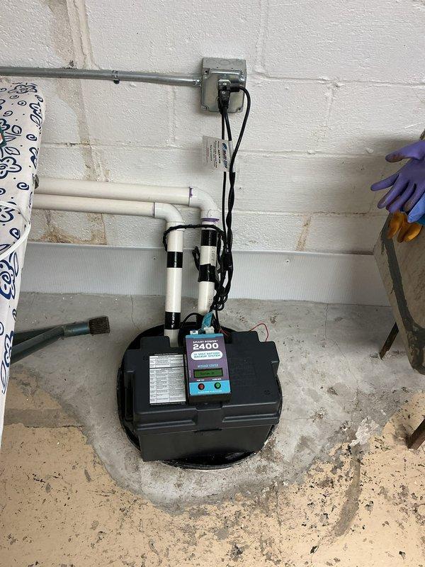 Responded to service call for water in basement with unknown source. Performed comprehensive inspection of 9-year-old sump pump system and basin to determine if equipment was contributing to water intrusion issue. Examined sump pump operation, float switches, discharge piping, and basin integrity. Verified pump functionality and checked all mechanical components submerged in basin water. Inspected PVC discharge lines, mounting assemblies, and electrical connections routed through wall-mounted conduit. Assessed concrete floor conditions around pump location, noting water exposure patterns and mineral deposits. Evaluated overall sump pump installation and drainage system to rule out equipment failure as source of basement water problem.
