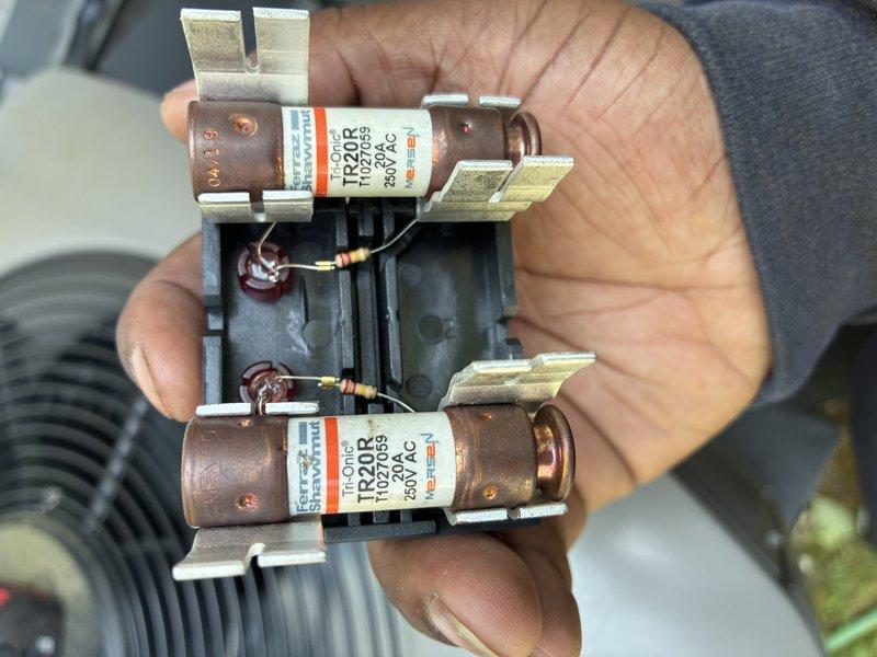 Completed MVP cooling maintenance visit on outdoor heat pump unit. Disassembled unit casing to access internal components, inspected condenser coils, and found significant dirt and debris accumulation on filter panels requiring cleaning. Inspected and tested fuse block assembly containing TR32R 250VAC fuses, which showed signs of oxidation on metal terminals. Documented equipment condition with photographs for service records.