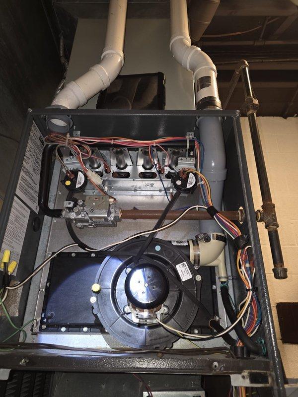 Responded to residential cooling complaint on 8-year-old air conditioning system. Upon arrival, performed diagnostic evaluation of HVAC unit using digital multimeter to test electrical components and control board functionality. Inspected furnace/air handler interior, examining green circuit board connections, blower motor assembly, and associated wiring harnesses. Verified proper voltage readings across multiple connection points including red, white, blue, brown, and yellow wire terminals. Examined blower motor operation and checked all electrical connections for secure contact and proper termination. Inspected heat exchanger assembly and verified PVC venting integrity. System tested and confirmed operational status upon completion of diagnostic procedures.