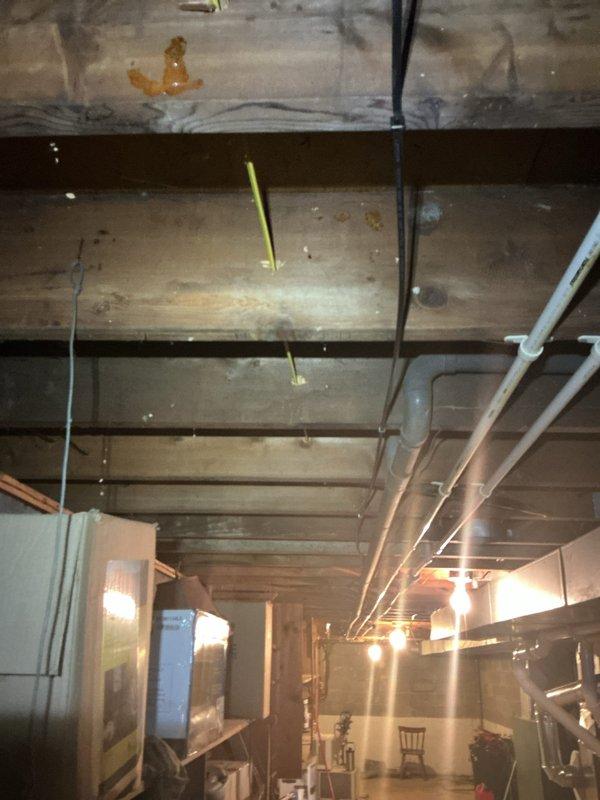 Completed AC circuit installation and electrical rewiring work in basement area. Installed new electrical conduit runs through floor joists, secured wiring with appropriate strapping and supports, and upgraded exterior electrical service meter with proper weatherproof seals and conduit connections to brick exterior wall.