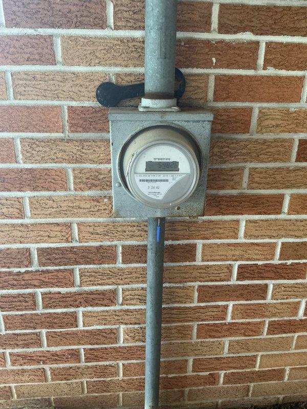 Completed AC circuit installation and electrical rewiring work in basement area. Installed new electrical conduit runs through floor joists, secured wiring with appropriate strapping and supports, and upgraded exterior electrical service meter with proper weatherproof seals and conduit connections to brick exterior wall.