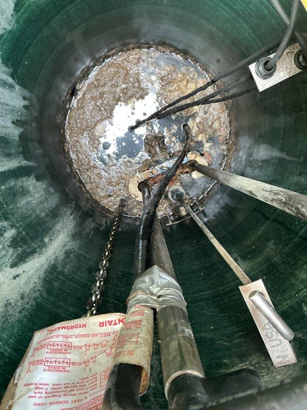 Responded to service call for malfunctioning grinder pump system requiring complete replacement. Upon arrival, inspected existing pump station and confirmed grinder pump failure. Removed old yellow pump unit from fiberglass wet well, which showed significant wear, sediment accumulation, and operational deterioration. Extracted pump assembly including mounting hardware, electrical connections, and discharge piping. Cleaned debris and sediment from bottom of station to ensure proper installation of replacement unit. Installed new grinder pump with appropriate mounting brackets, connected electrical wiring per manufacturer specifications, and verified all plumbing connections were secure. Tested system operation to confirm proper grinding function and discharge performance before restoring station to service.