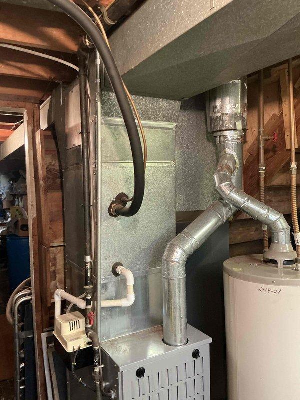 Conducted on-site assessment of aging 1990s residential air conditioning system for replacement estimate. Evaluated existing indoor furnace unit with connected ductwork in basement utility area and outdoor condenser unit with disconnect box, documented current equipment specifications and installation conditions, and photographed both components to provide comprehensive replacement proposal for obsolete HVAC system.
