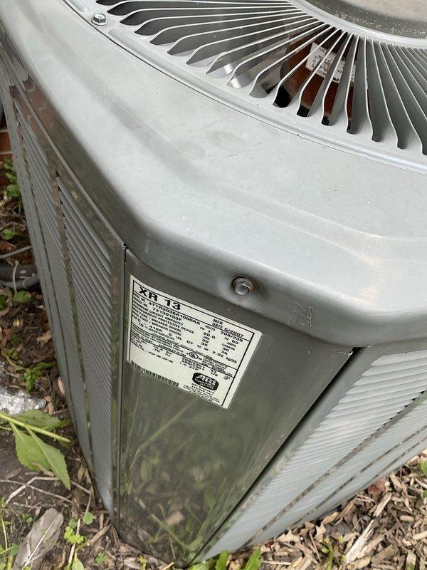 Assessed 19-year-old York air conditioning condenser unit with confirmed refrigerant leak exceeding 3000 units. Documented existing outdoor unit condition showing weathering and age-related deterioration, photographed installation site including concrete pad placement and surrounding landscaping for replacement estimate preparation. Provided comprehensive equipment replacement quote for new system installation.