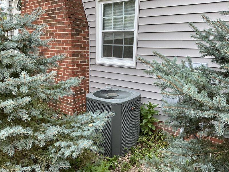 Assessed 19-year-old York air conditioning condenser unit with confirmed refrigerant leak exceeding 3000 units. Documented existing outdoor unit condition showing weathering and age-related deterioration, photographed installation site including concrete pad placement and surrounding landscaping for replacement estimate preparation. Provided comprehensive equipment replacement quote for new system installation.