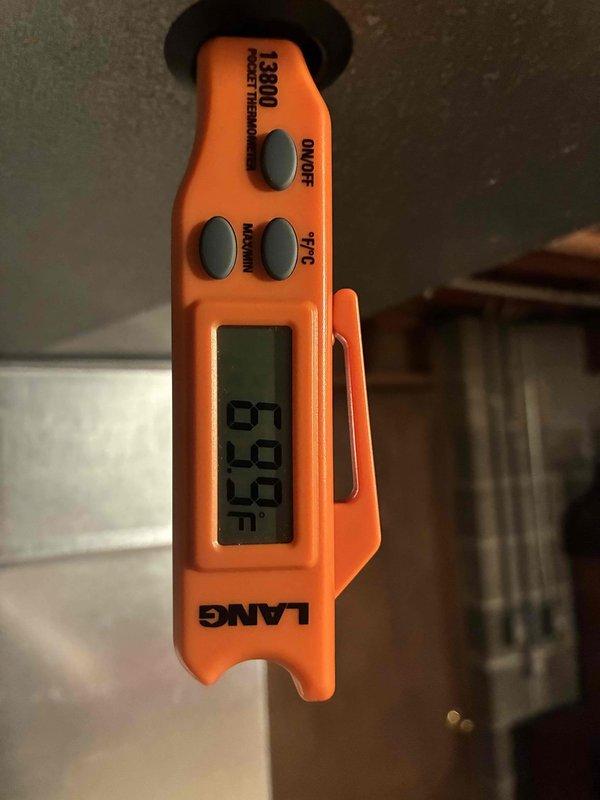 Completed MVP cooling maintenance visit on residential air conditioning system. Performed temperature diagnostics using digital thermometer, recording supply air temperature of 63.2°F to verify proper cooling operation. Inspected outdoor condenser unit, noting accumulated dirt and debris on front intake grille and coil surfaces. Unit operational at time of service with fan motor running properly. Documented equipment condition through photographs for service records.