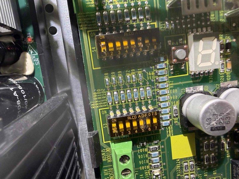 Completed scheduled BS-MVP cooling maintenance visit on 2-year-old outdoor unit. Performed comprehensive system inspection including visual examination of control board and electrical components. Documented circuit board condition showing proper operation of capacitors, DIP switches, LED display, and all surface-mount components. Verified all wire connections secure with proper labeling intact across red, yellow, blue, orange, brown, white, and black conductors. Inspected interior control panel assembly with stacked circuit boards and confirmed all electronic components functioning within normal parameters. Unit operating efficiently with no issues identified during preventive maintenance service.
