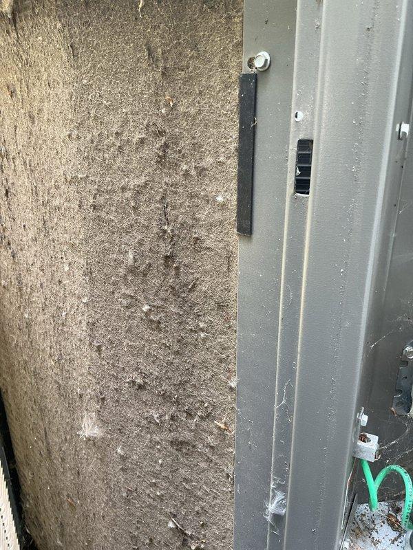 Responded to service call for 5-year-old residential air conditioning system. Upon arrival, performed comprehensive system inspection of outdoor condensing unit. Found dirty air filter with significant dust accumulation affecting airflow efficiency. Cleaned unit exterior and base area where debris and organic matter had accumulated along concrete pad foundation, noting algae growth on pad surface. Replaced contaminated filter with new unit, cleared gravel bed area around equipment, and verified all mounting hardware remained secure. Tested system operation following service completion to ensure proper function and adequate cooling performance.