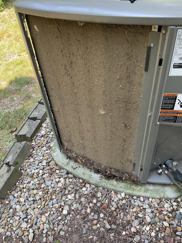 Responded to service call for 5-year-old residential air conditioning system. Upon arrival, performed comprehensive system inspection of outdoor condensing unit. Found dirty air filter with significant dust accumulation affecting airflow efficiency. Cleaned unit exterior and base area where debris and organic matter had accumulated along concrete pad foundation, noting algae growth on pad surface. Replaced contaminated filter with new unit, cleared gravel bed area around equipment, and verified all mounting hardware remained secure. Tested system operation following service completion to ensure proper function and adequate cooling performance.