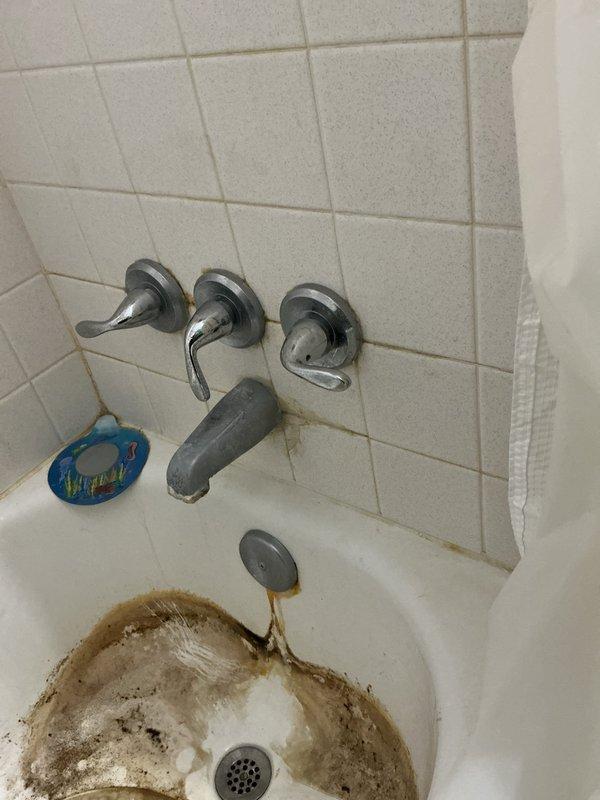 Responded to service call for leaking bathroom faucet. Upon arrival, inspected three-handle tub faucet fixture with chrome handles and central spout. Identified source of leak and performed necessary repairs to stop water dripping. Tested all three handles and spout for proper operation and verified complete seal with no further leakage detected upon completion.