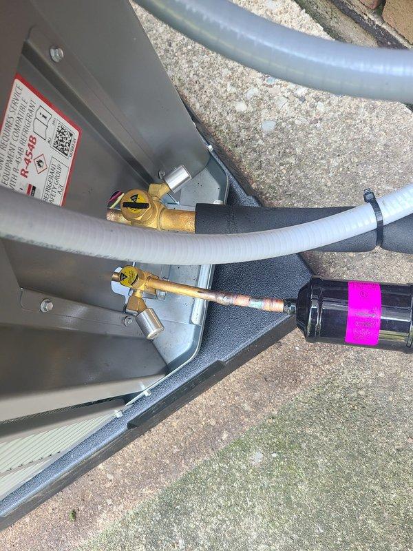 Completed installation of new air conditioning system with evaporator coil. System was evacuated to 130.9 microns and held vacuum within acceptable parameters, passing decay test after 12 minutes and 27 seconds of total elapsed time. All refrigerant lines were properly insulated and secured, disconnect box mounted, and filter drier installed with appropriate service valves for future maintenance access.