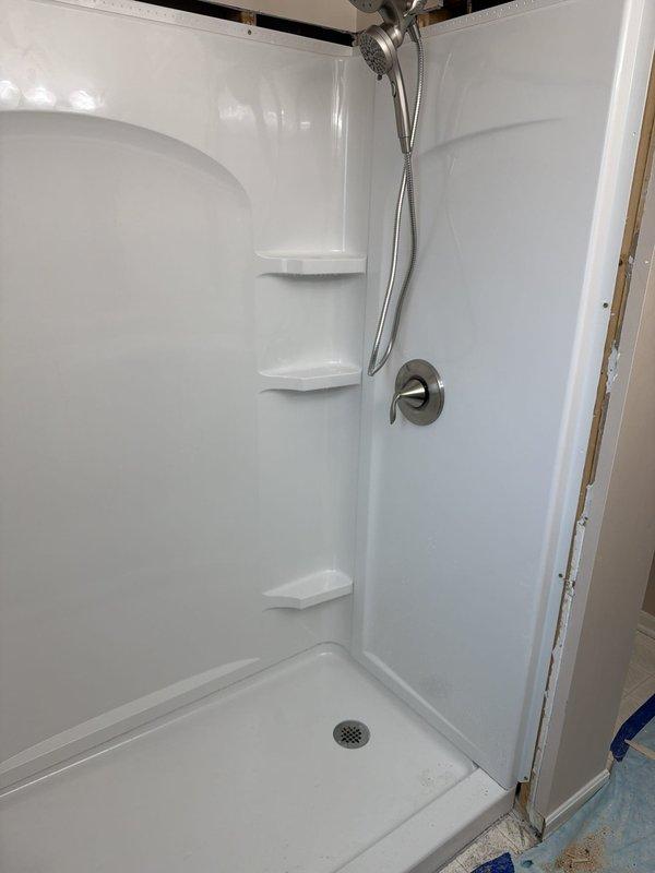Completed full shower replacement including removal of existing fixtures and installation of new 32x60 Sterling Kohler shower base and surround system. Installed new single-handle shower valve with chrome trim and Moen Magnetix handheld showerhead with flexible metal hose. Connected new shower assembly to existing 1-1/2 inch drain line, ensuring proper pitch and watertight seal. Mounted three integrated corner shelving units within the surround for storage accessibility. All plumbing connections tested and verified for proper operation and no leaks. Work completed with one helper over full-day installation.