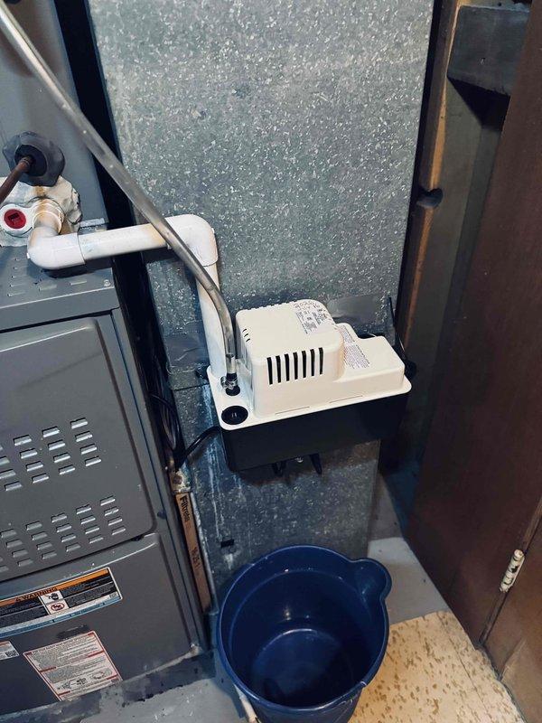 Responded to warranty call for recently installed HVAC system experiencing air leakage around refrigerant line penetration into outdoor unit and condensate reservoir door leakage. Inspected installation and documented existing conditions with photographs showing furnace/air handler, condensate pump assembly, and drainage system components. Identified water staining on concrete floor near equipment and confirmed active condensate management issues requiring attention to prevent further moisture damage to mechanical room.