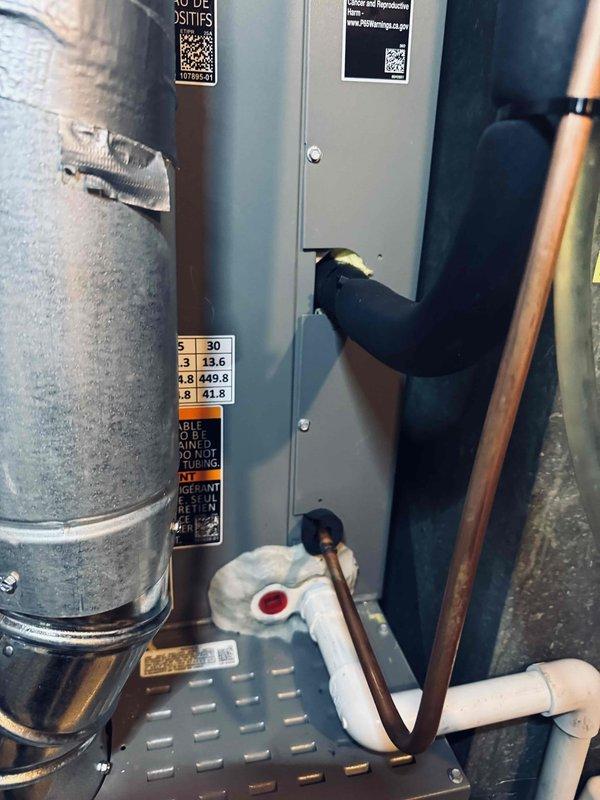 Responded to warranty call for recently installed HVAC system experiencing air leakage around refrigerant line penetration into outdoor unit and condensate reservoir door leakage. Inspected installation and documented existing conditions with photographs showing furnace/air handler, condensate pump assembly, and drainage system components. Identified water staining on concrete floor near equipment and confirmed active condensate management issues requiring attention to prevent further moisture damage to mechanical room.