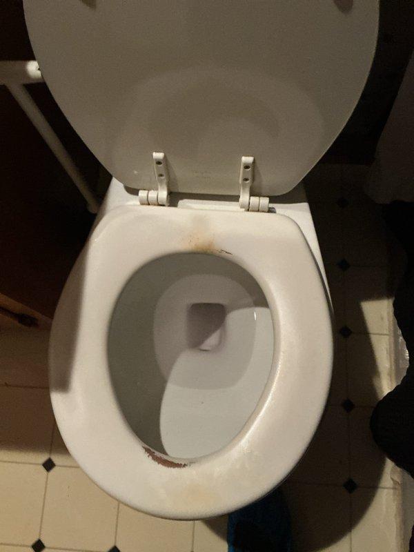 Responded to service call for clogged toilet on first floor. Upon arrival, assessed the fixture and surrounding area, documenting existing conditions including mineral deposits and staining on the bowl and seat rim. Successfully cleared the blockage and restored proper drainage and flushing function. Verified toilet operation and left fixture in working order with plunger available for homeowner use.