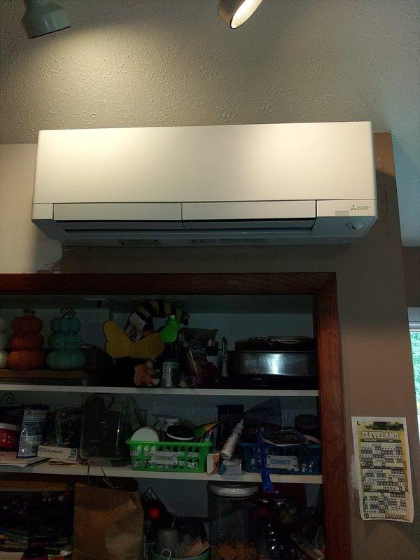 Completed installation of single-head Mitsubishi mini-split system in residential space. Mounted indoor air handler unit on interior wall above shelving area, installed outdoor condenser, ran refrigerant lines and electrical connections, and performed system startup and testing. Verified proper operation with temperature readings confirming unit cooling to 68.7°F at time of completion.
