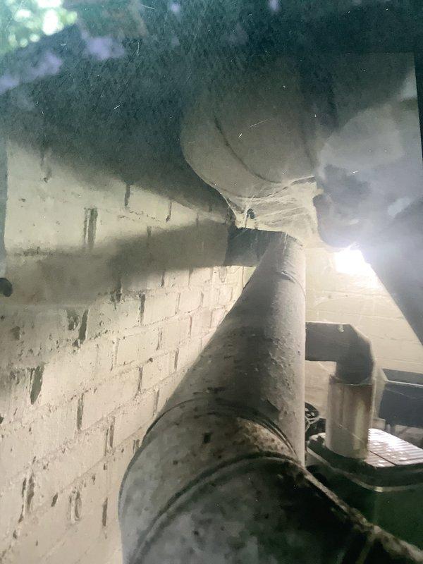 Conducted on-site evaluation of existing HVAC system for furnace replacement and installation estimate. Inspected current air handler unit with open access panel, assessed condition of ductwork including insulated supply trunk line showing age-related deterioration and staining, and evaluated mechanical room configuration. Documented equipment specifications, existing refrigerant line connections, electrical service, and spatial constraints within basement utility area. Photographed concrete block foundation walls, floor joist clearances, and current equipment mounting to determine replacement unit sizing and installation requirements for comprehensive furnace replacement proposal.