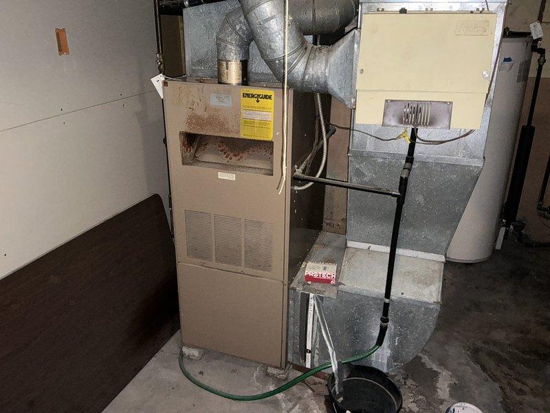 Completed comprehensive assessment of existing HVAC system experiencing no cooling condition and whistling sound concerns. Evaluated beige furnace unit with integrated air handler/humidifier, noting visible interior burner discoloration and signs of wear throughout the system. Documented existing ductwork configuration with metallic supply and return runs showing dust accumulation and age-related deterioration. Assessed copper refrigerant lines, black gas piping, and associated plumbing connections in basement utility space. Provided detailed replacement estimate for complete furnace and air conditioning system upgrade to address cooling failure and operational noise issues while improving overall system efficiency and reliability.
