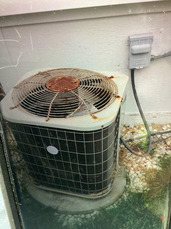Responded to hail damage assessment request for outdoor mini-split condenser unit. Conducted thorough visual inspection of equipment, documenting extensive rust staining on fan guard and top rim, along with weathered concrete pad showing algae growth. Performed electrical diagnostics using digital multimeter to verify system functionality and assess potential component damage from hail impact. Documented unit condition with photographs and provided customer with detailed repair quote based on findings.