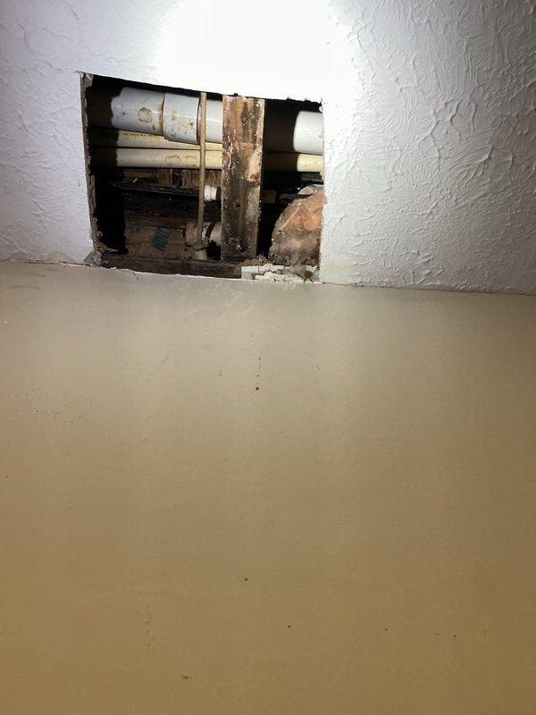 Responded to a shower leak causing water damage to the kitchen ceiling below. Upon arrival, accessed the plumbing system through the wall to locate the source of the leak. Investigation revealed corroded plumbing components with significant rust staining on vertical supply lines behind the shower/tub enclosure. Cut an access opening in the wall to expose the affected pipes and framing. Identified the failed connection causing water to penetrate through the floor assembly into the ceiling cavity below. Repaired the leaking plumbing connections, replaced corroded components, and verified proper water flow and drainage. Documented the condition of existing pipes and repair work with photographs for record-keeping purposes.