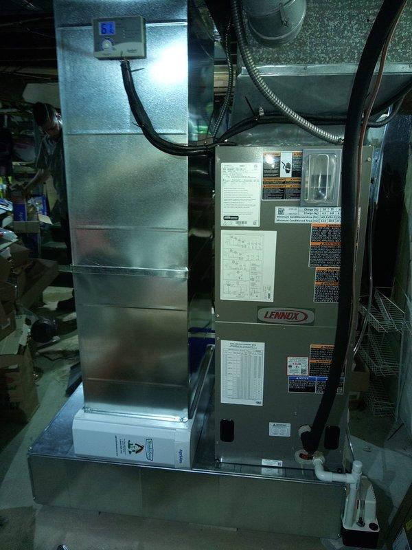 Completed full HVAC system installation including Lennox air handler with heat strips and heat pump in residential basement utility room. Installation features proper ductwork configuration with galvanized sheet metal assembly, digital thermostat control, condensate pump with PVC drainage system, and all necessary flexible duct connections to existing infrastructure.