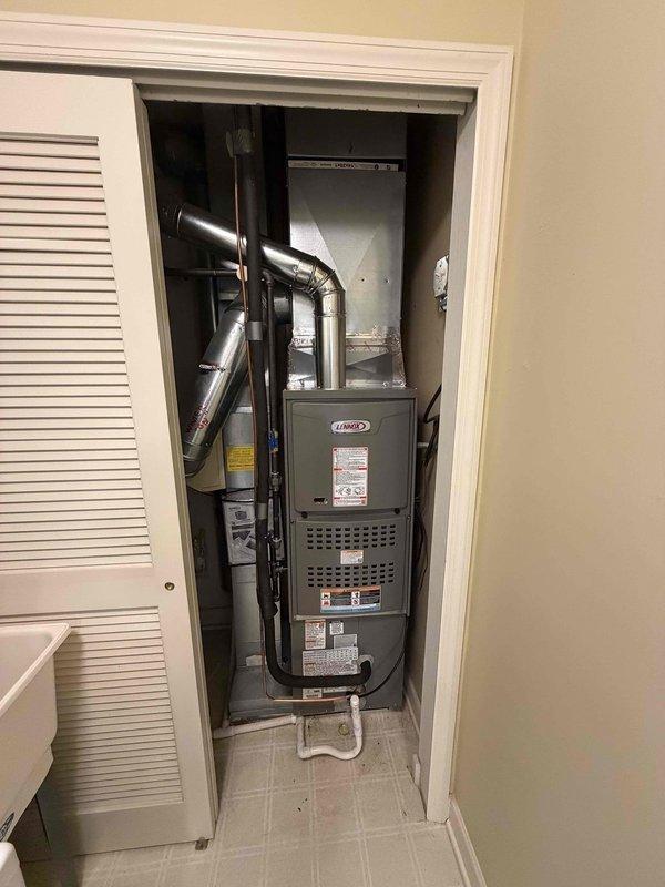 Completed full HVAC system installation including 80% efficient downflow furnace and air conditioning unit. Installed new Lennox furnace in utility closet with properly configured downflow ductwork, connected black metal supply ducts with appropriate elbows for confined space routing, and established PVC condensate drain line. Mounted outdoor AC condenser unit, installed dual fuse disconnect assembly with proper wire terminations and protective housing on exterior wall, and verified all electrical connections meet code requirements. System tested and operational.