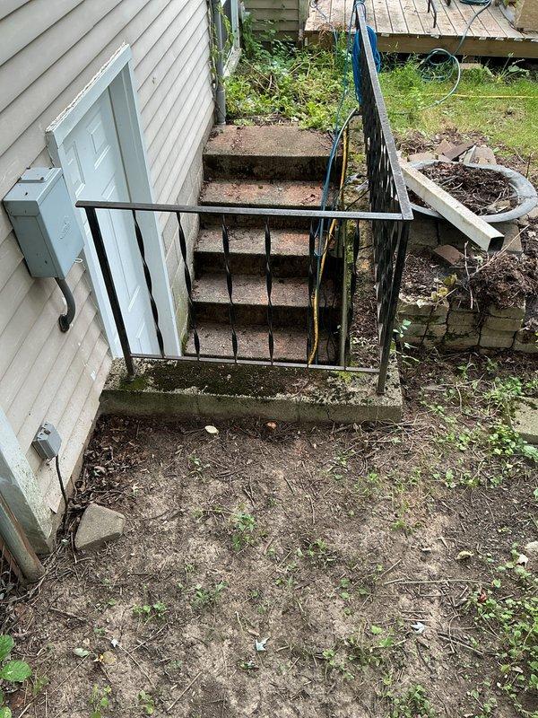 Responded to a non-draining ground water drain located at the bottom of exterior basement stairs near storm door. Upon arrival, found concrete stairwell with significant water staining, moss growth, and organic buildup indicating chronic drainage issues. Customer had been utilizing two pumps during heavy rainfall events to prevent water intrusion into basement due to drain failure.

Inspected drain system at base of stairwell and identified blockage preventing proper storm water discharge. Cleared accumulated debris, sediment, and organic matter from drain opening and line. Verified water flow and drainage capacity restored to functional operation. Tested system to ensure proper water evacuation from stairwell area, eliminating need for temporary pump usage during precipitation events.