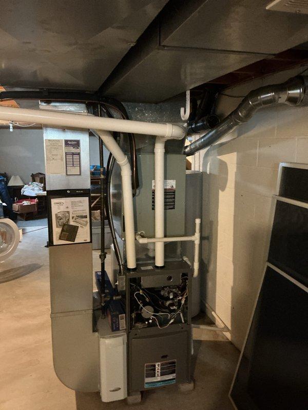 Completed installation of new air conditioning system and evaporator coil in residential basement location. Unit was properly positioned, connected to existing ductwork infrastructure with black flexible and metal supply runs, and integrated with vertical furnace system including PVC exhaust and intake venting routed along ceiling joists. All electrical connections were made to panel, refrigerant lines installed, system tested and verified operational.