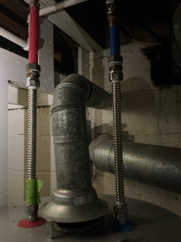 Responded to report of water leak from second-floor toilet penetrating through first-floor kitchen ceiling. Upon investigation, accessed plumbing assembly in basement/crawl space and identified source of leak at toilet supply line connections. Inspected T-joint assembly and flexible supply hoses (hot and cold water lines) for signs of failure or loose fittings. Tightened connection points at the metal junction and verified secure attachment of braided supply lines. Tested water flow at kitchen sink to confirm proper system operation and checked for active leaking. Monitored ceiling area and plumbing connections to ensure leak was resolved. All connections secured and system restored to proper working order with no further evidence of water intrusion.