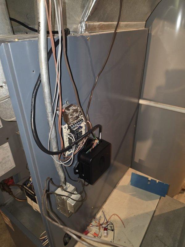 Completed installation of Lennox heat pump system integrated with existing oil furnace setup. Indoor air handler unit mounted in basement utility area with refrigerant lines, electrical connections, and ductwork professionally installed and secured. Outdoor condenser unit positioned on concrete pad against exterior wall with proper clearances maintained for airflow and serviceability.