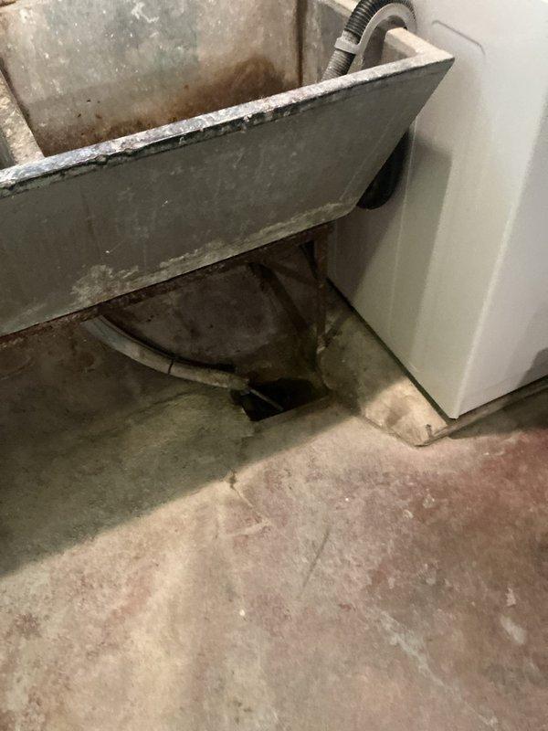 Completed backflow preventer installation at residential property with service call scheduled for morning arrival window. Assessed utility area showing previous water damage and staining on concrete floor near existing water heater, with drainage pan exhibiting age-related deterioration. Installed backflow device per code requirements and documented installation with photos for service records.