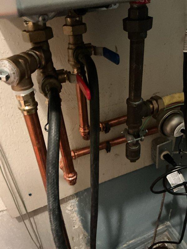 Completed annual maintenance descaling service on tankless water heater system. Performed full flush and descale procedure using appropriate descaling solution to remove mineral buildup and maintain optimal unit performance. Inspected all associated plumbing connections, isolation valves, and pressure relief components during service, confirming proper operation of red-handled NIBCO ball valves and verifying integrity of copper and galvanized pipe connections throughout the system.