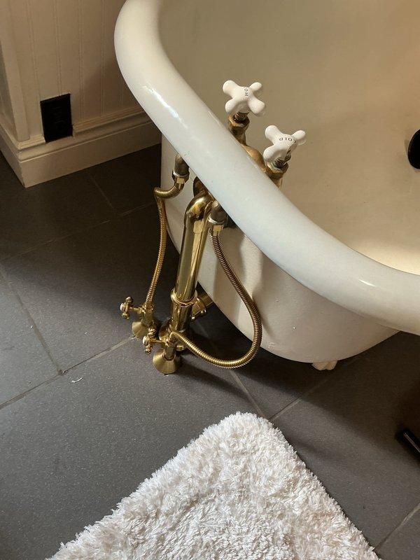 Replaced existing supply lines on clawfoot bathtub with customer-supplied brass-finish supply lines. The vintage-style tub features exposed plumbing with decorative brass fittings and porcelain cross-handle taps. Installation completed successfully with no additional parts required.