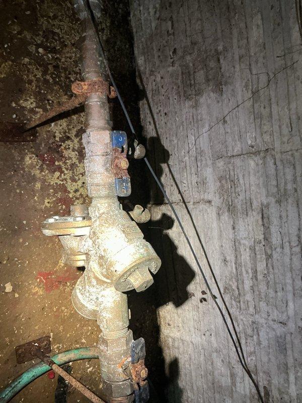 Completed annual backflow prevention device testing on a ninety-year-old residential property. Upon arrival, inspected the existing backflow assembly located in the basement area, which exhibited significant age-related corrosion, mineral deposits, and surface oxidation consistent with the home's age. Performed comprehensive testing procedures on the backflow preventer to verify proper operation and compliance with local plumbing codes. All test ports, check valves, and relief valve components were evaluated for functionality. The device passed testing requirements with acceptable pressure differentials and check valve sealing. Documented the assembly's condition with photographic records showing the corroded brass fittings, oxidized piping, and overall wear patterns typical of decades-old installations. No leaks, failures, or operational deficiencies were detected during testing procedures. The backflow prevention system is functioning as designed to protect the potable water supply f