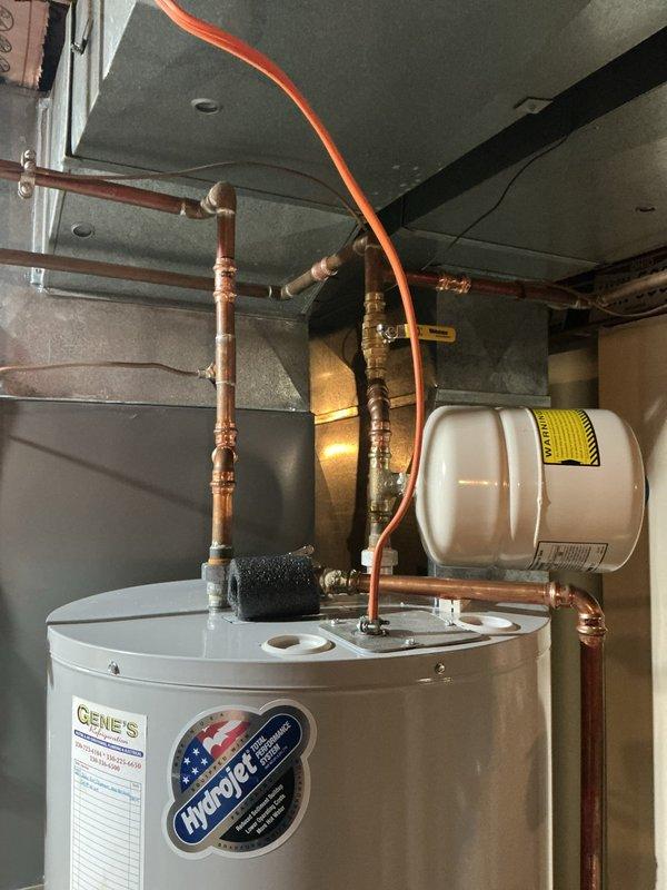 Responded to service call for leaking water heater valve on an 8-year-old Hydro+ tanked water heater unit. Upon inspection, identified active leak originating from valve assembly and confirmed existing drain pan beneath unit was cracked and required replacement. Documented installation with photographs showing copper supply lines, expansion tank, and current water heater configuration in mechanical room. Performed diagnostic assessment and provided repair recommendations to address valve leak and replace damaged drain pan to prevent potential water damage to flooring and surrounding area.