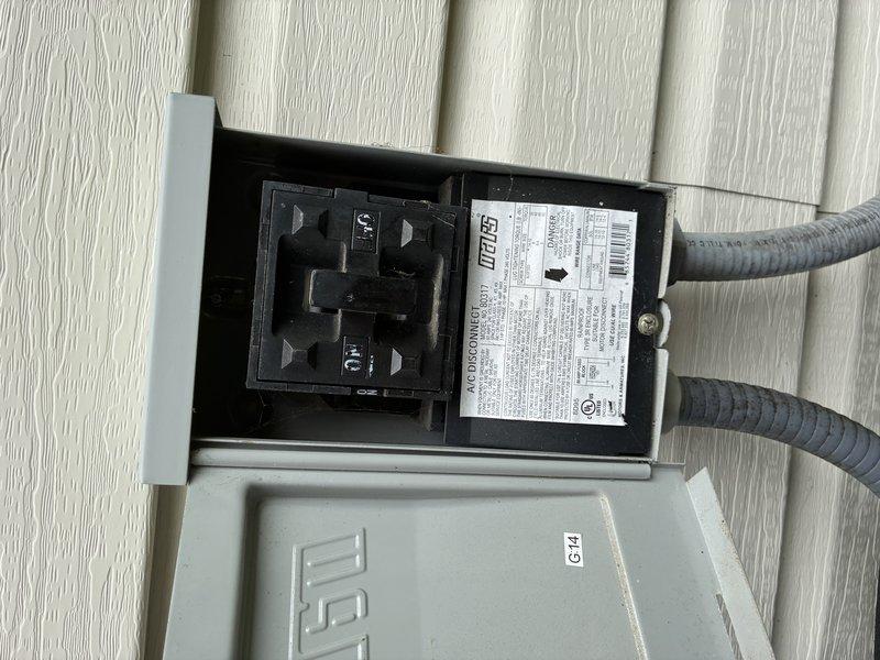 Completed routine MVP cooling maintenance visit for residential air conditioning system. Inspected and documented air filter condition, showing moderate dust accumulation with visible particulate buildup in chevron pattern indicating normal filtration operation. Verified electrical disconnect box and external components, confirming proper installation and accessibility of safety disconnect switch with dual conduit connections to outdoor unit.