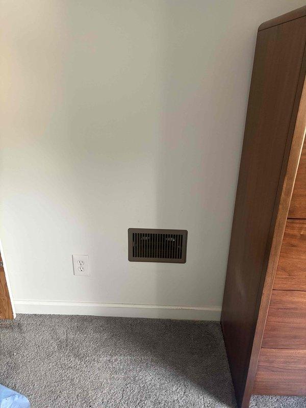 Completed installation of mini split system with air handler and associated ductwork in residential property. Installed floor register in bedroom with proper placement near baseboard, ensuring adequate airflow distribution. Routed flexible ductwork through attic space, connecting to existing ventilation infrastructure and securing around vertical vent stack with appropriate clearances maintained throughout installation.