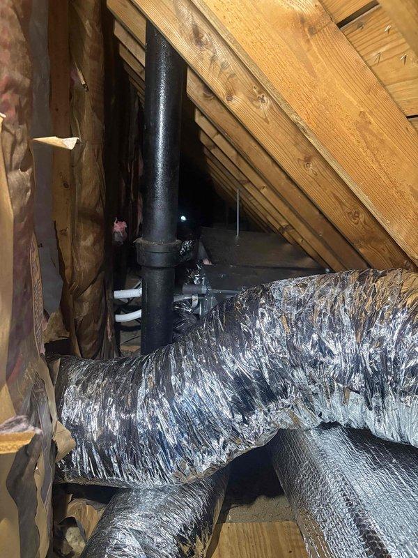 Completed installation of mini split system with air handler and associated ductwork in residential property. Installed floor register in bedroom with proper placement near baseboard, ensuring adequate airflow distribution. Routed flexible ductwork through attic space, connecting to existing ventilation infrastructure and securing around vertical vent stack with appropriate clearances maintained throughout installation.