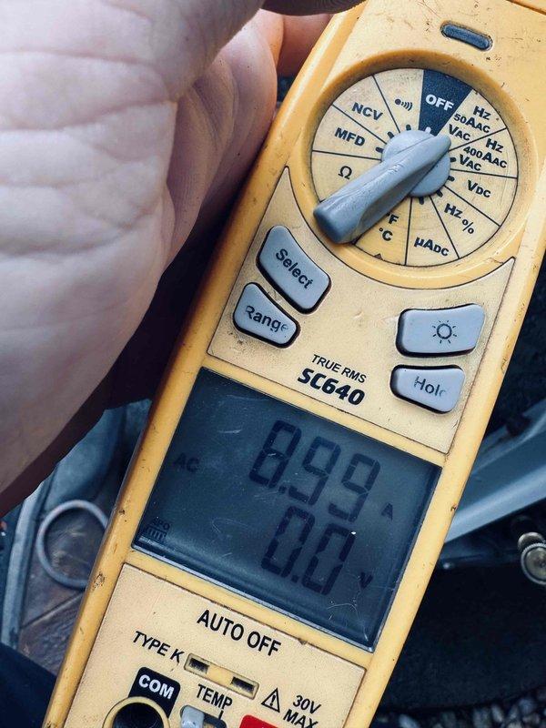 Completed comprehensive tune-up on air conditioning system over 20 years old. Performed electrical diagnostics using digital multimeter to verify system voltage and capacitance readings, with measurements indicating 8.99 units on primary circuit. Inspected blower wheel assembly and found light dust accumulation on blades but component remained in functional condition with proper blade spacing and shaft alignment intact.