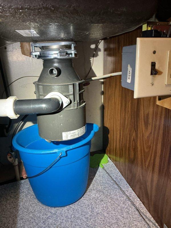 Completed garbage disposal installation in kitchen of 1952-built residential home. Removed existing drain assembly and mounted customer-supplied disposal unit beneath stainless steel sink basin. Connected discharge piping to existing plumbing system and verified electrical connection to wall-mounted switch. Tested unit for proper operation, drainage, and leaks. Disposal is now fully functional with no leaks detected.