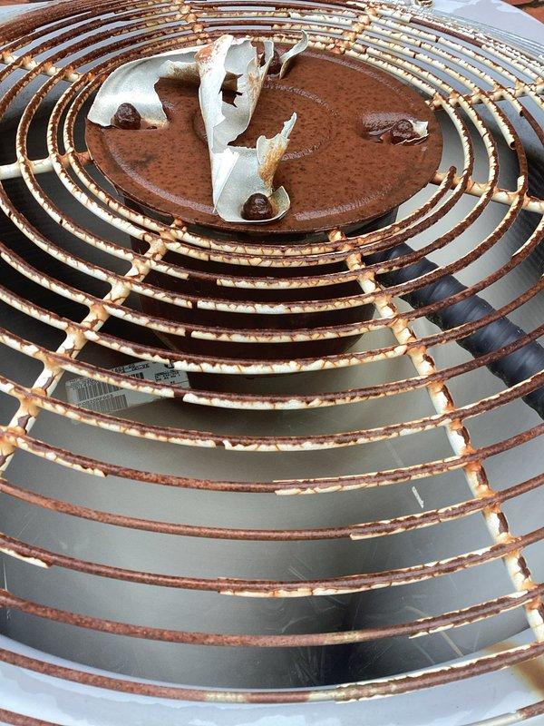 Responded to service call for two attic-mounted A/C units with one non-operational system. Upon inspection, discovered outdoor condenser unit with heavily corroded fan guard and accumulated debris including foam insulation material obstructing proper airflow. Cleared debris from fan assembly, inspected refrigerant lines and electrical connections, and verified both systems returned to normal operation.