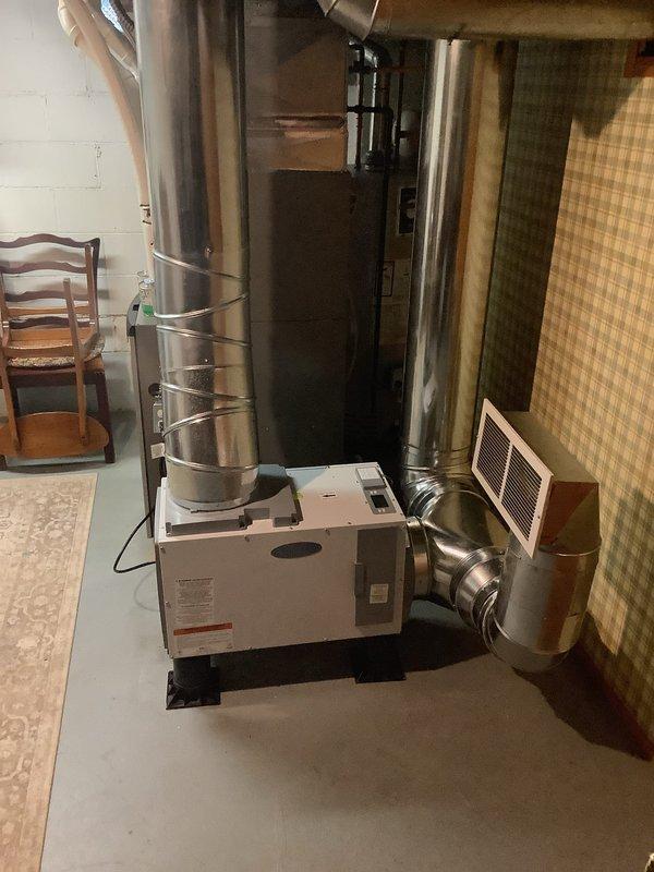 Diagnosed dehumidifier with complete loss of refrigerant charge requiring full unit replacement. Replaced existing dehumidifier with new unit featuring 10-inch duct connection, which necessitated replacement of existing ductwork to accommodate proper sizing. Installation required approximately 5 hours of labor with assistance from second technician for approximately 20 minutes during equipment positioning and ductwork connection.