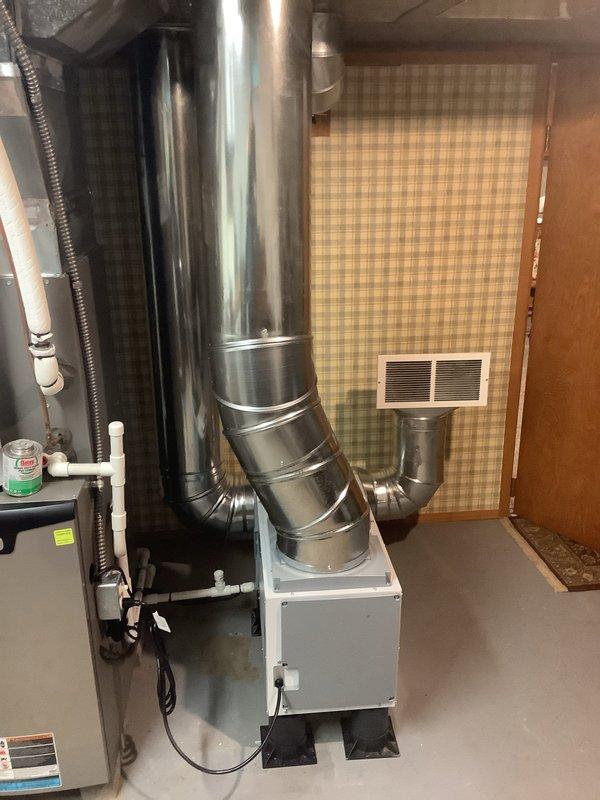 Diagnosed dehumidifier with complete loss of refrigerant charge requiring full unit replacement. Replaced existing dehumidifier with new unit featuring 10-inch duct connection, which necessitated replacement of existing ductwork to accommodate proper sizing. Installation required approximately 5 hours of labor with assistance from second technician for approximately 20 minutes during equipment positioning and ductwork connection.