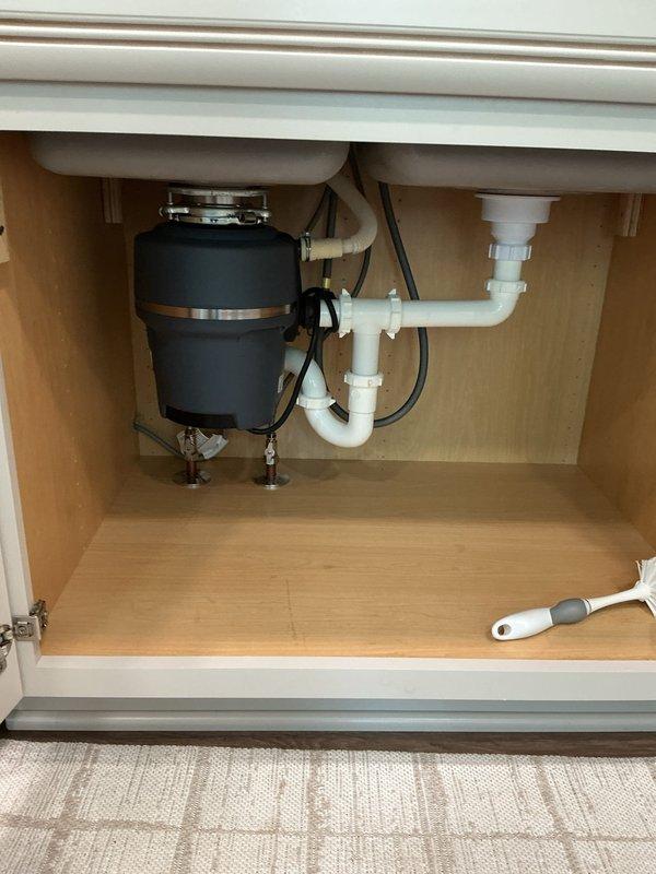 Responded to service call for a 4-year-old garbage disposal unit reported to be struggling, with customer suspecting the wall switch as the cause. Upon arrival, performed diagnostic inspection of the disposal unit mounted beneath the kitchen sink. Examined electrical connections, tested wall switch functionality, and assessed the disposal motor and grinding mechanism. Inspected the complete under-sink plumbing assembly including the P-trap configuration, drain connections, and mounting hardware. Verified proper electrical supply to the unit and evaluated mechanical operation. Documented existing conditions including mineral deposit buildup around drain openings in the stainless steel sink basin. Completed troubleshooting procedures to identify the root cause of the disposal's performance issues.