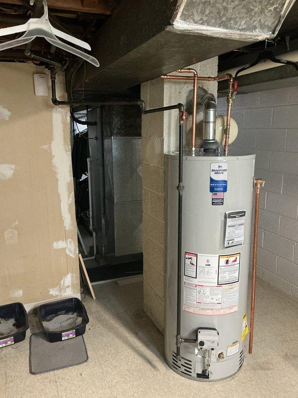 Completed installation of 50-gallon Bradford White natural gas water heater with ball valve and expansion tank, converting from existing tankless system. Repiped gas and water lines with copper connections, discontinued electrical service with proper junction box installation in ceiling, and sealed flue pipe at chimney connection. All safety labels and specifications verified, unit tested and operational per manufacturer requirements.