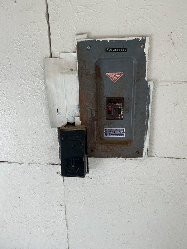 Conducted on-site evaluation of existing electrical service panel and grounding system for potential 200-amp service upgrade. Inspected aging electrical panel with visible rust staining and weathering, documented current service configuration including main breaker assembly and conduit connections. Assessed basement utility area electrical infrastructure, examined multiple panels and conduit routing to determine scope of work required for service upgrade and proper grounding installation.