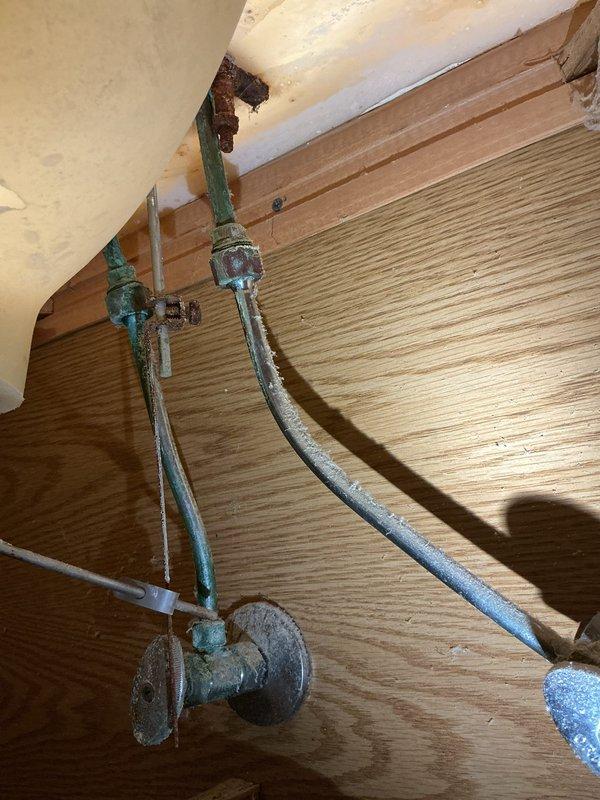 Responded to service call for clogged toilet and leaking faucet. Upon inspection, identified heavily corroded copper water supply lines and shutoff valves with significant green patina indicating prolonged moisture exposure and oxidation. Addressed the toilet clog and repaired the leaking faucet by replacing deteriorated washers and sealing components. Documented existing corrosion on supply lines and valves for future maintenance considerations.