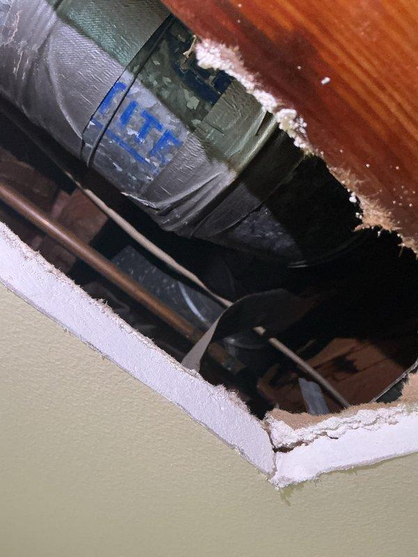 Responded to callback regarding ceiling discoloration and paint bubbling on first floor directly below second floor sink that was previously unclogged. Upon inspection, accessed ceiling cavity and documented water damage to drywall and paint surface. Investigation revealed potential leak from plumbing assembly above, with visual inspection of copper piping and drain lines in ceiling space. Photographed affected ceiling area and accessed mechanical space to assess plumbing connections and HVAC components in vicinity of reported damage.