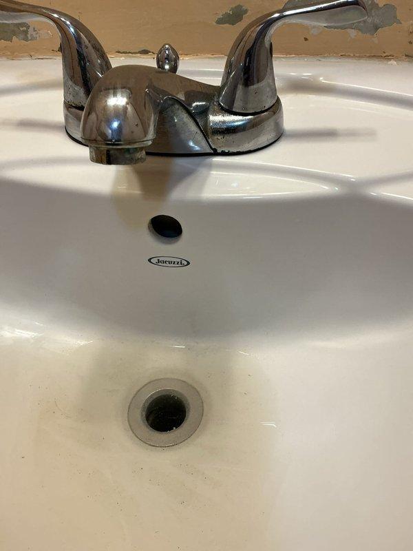 # Plumbing Service Report

Responded to service call at group home facility for two clogged bathroom sinks. Upon inspection, found white porcelain Jacuzzi bathroom sinks with chrome two-handle faucets experiencing drainage issues. Cleared obstructions from both sink drain lines using appropriate drain cleaning equipment and techniques. Inspected accessible plumbing connections beneath sinks, noting existing corrosion and mineral deposits on visible piping, though these pre-existing conditions did not impact the immediate drainage repair. Tested water flow and drainage in both bathroom sinks after clearing blockages, confirming proper function and adequate drainage speed. Both sinks now draining properly with no standing water or slow drainage issues remaining.